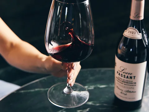 Red wine being poured beside a bottle at The Room